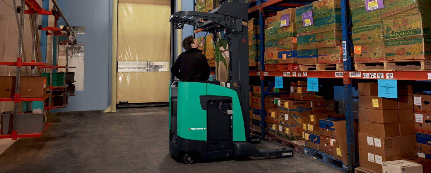 Man driving Mitsubishi reach truck pulling box from rack